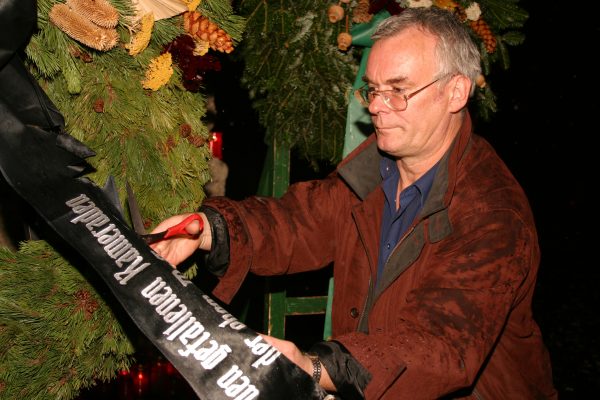 Hans Türk schneidet 2005 ein Kranzschleife von einem SS-Kranz ab